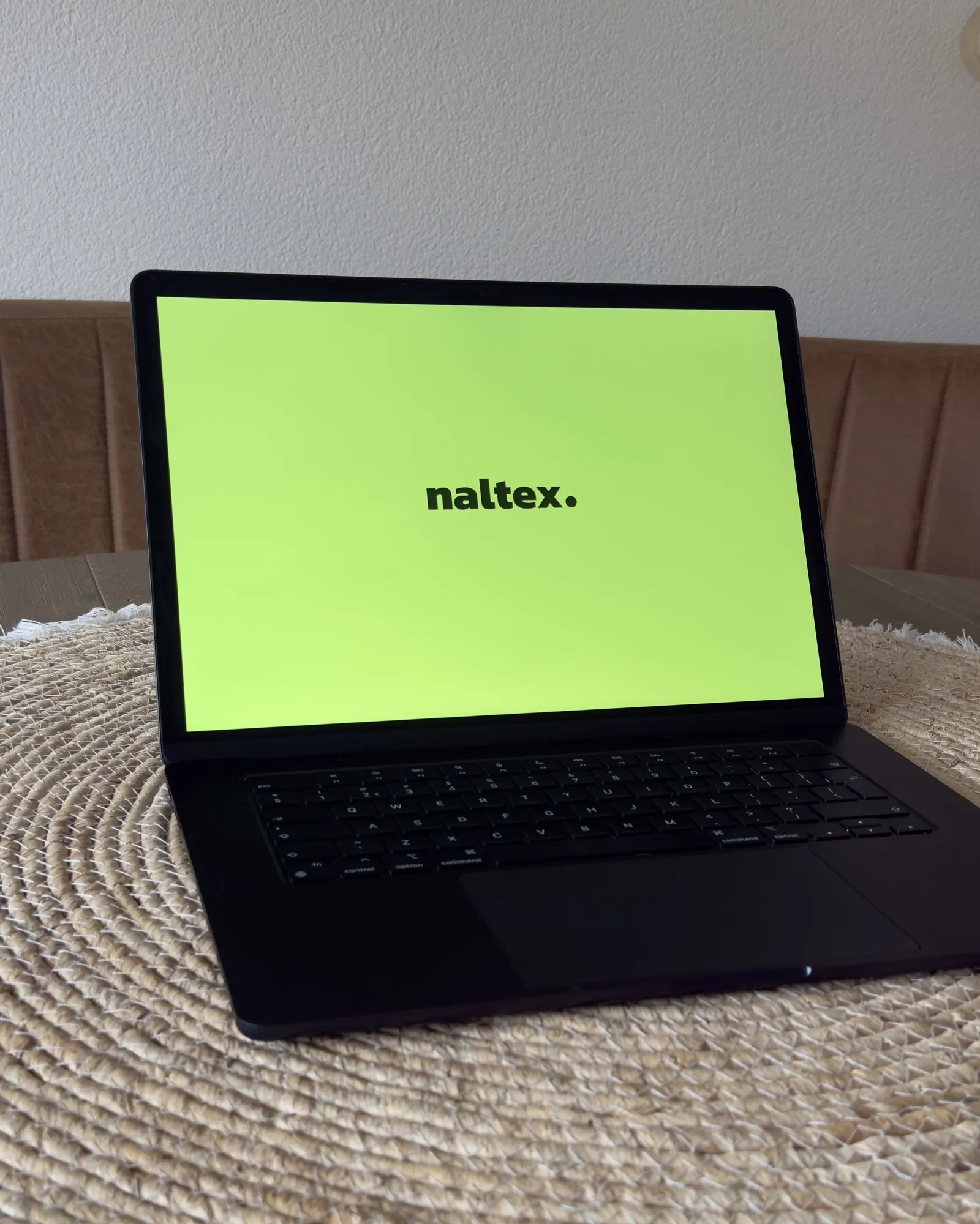 De MacBook van Naltex met de Naltex-wallpaper op de eettafel in Papendrecht